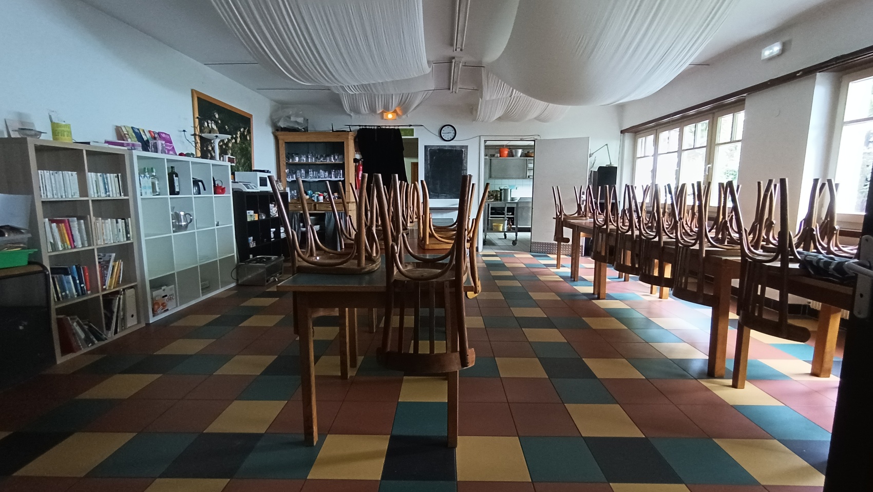 grand espace avec deux grandes tables des chaises et une bibliothèque