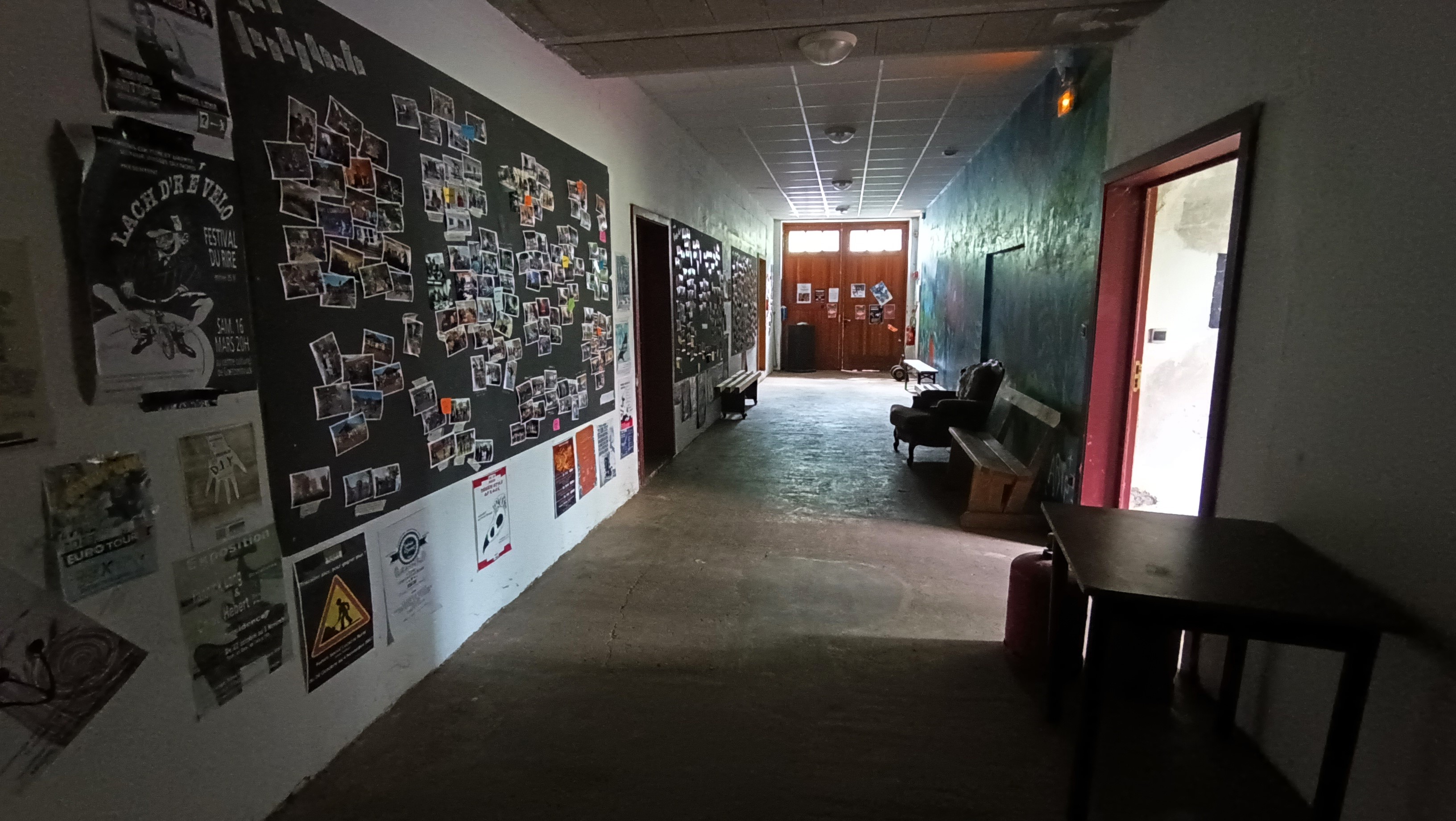 couloir large avec des panneaux d'affichage une table et des bancs le long des murs